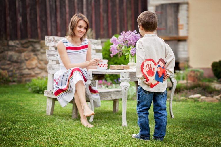 Beautiful mom, having coffee in a backyard, young cute child giv